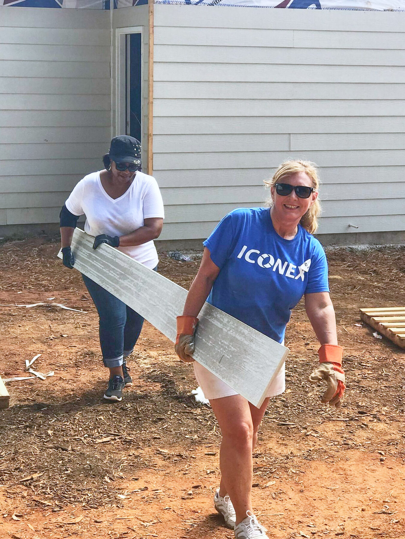 ICONEX Volunteers from ICONEX carrying lumber on a build site.