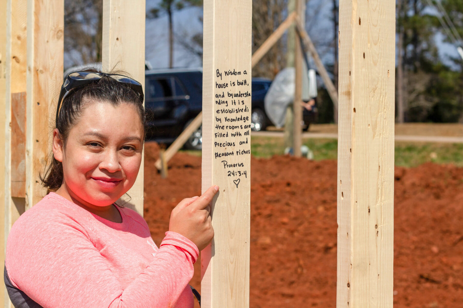 Habitat Homeowner pointing to a message written on one of the studs of her home.